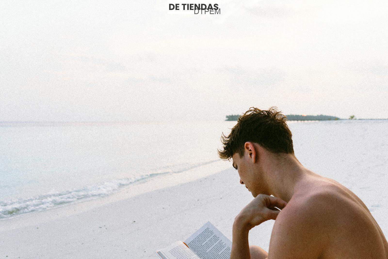 Topless Man Reading Book While Seating at Beach